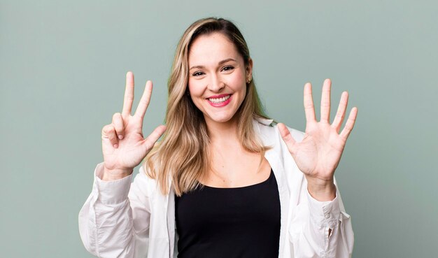 Photo smiling and looking friendly showing number eight or eighth with hand forward counting down