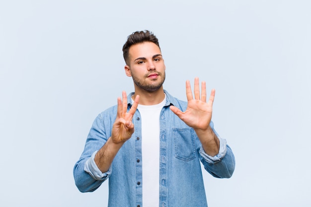 smiling and looking friendly, showing number eight or eighth with hand forward, counting down