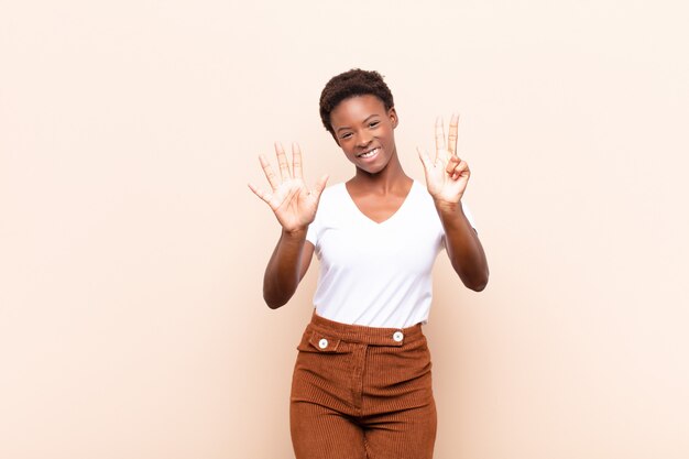 smiling and looking friendly, showing number eight or eighth with hand forward, counting down