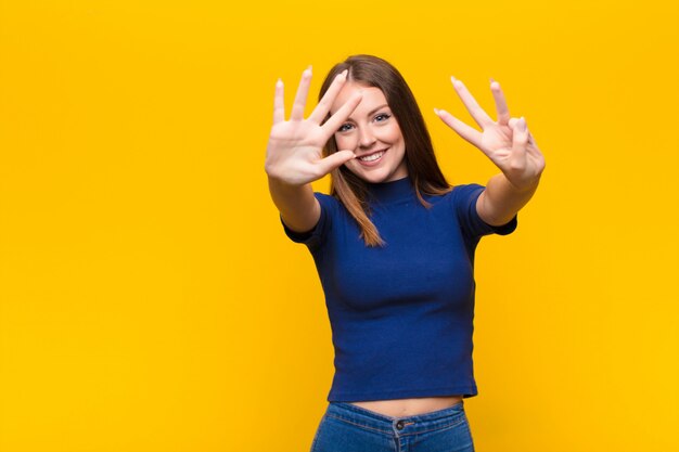 smiling and looking friendly, showing number eight or eighth with hand forward, counting down