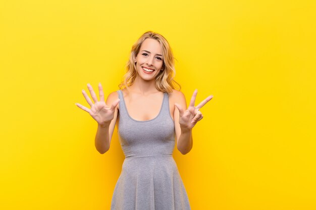 Smiling and looking friendly, showing number eight or eighth with hand forward, counting down