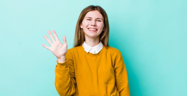 Smiling and looking friendly showing number five or fifth with hand forward counting down