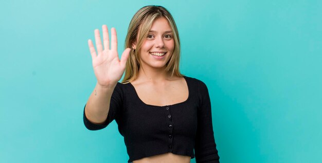 Smiling and looking friendly showing number five or fifth with hand forward counting down