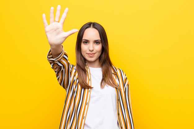 smiling and looking friendly, showing number five or fifth with hand forward, counting down