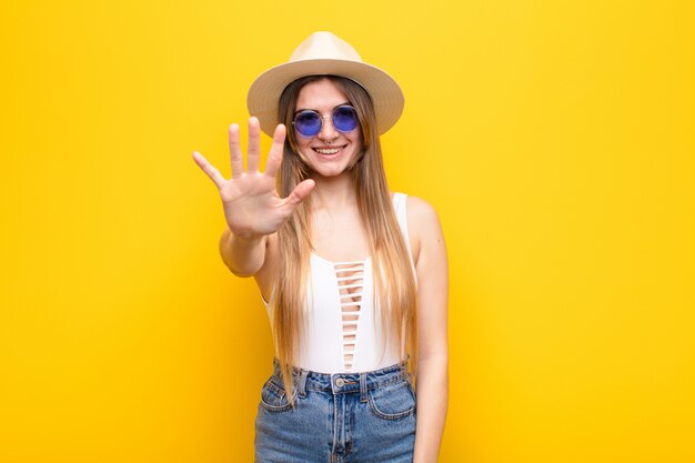 smiling and looking friendly, showing number five or fifth with hand forward, counting down