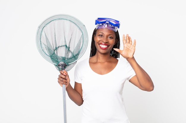 Smiling and looking friendly, showing number five with goggles and fisher net