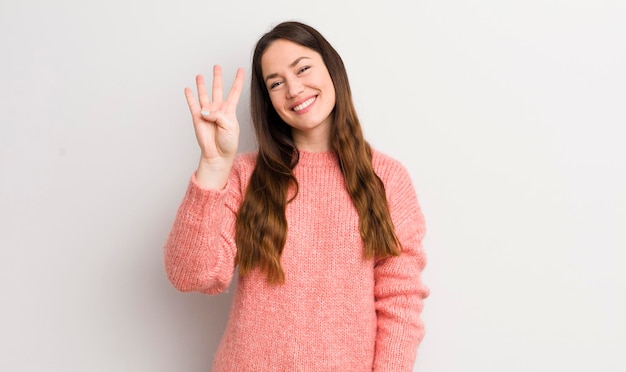 Smiling and looking friendly showing number four or fourth with hand forward counting down