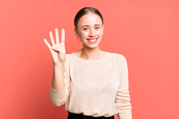 Smiling and looking friendly showing number four or fourth with hand forward counting down