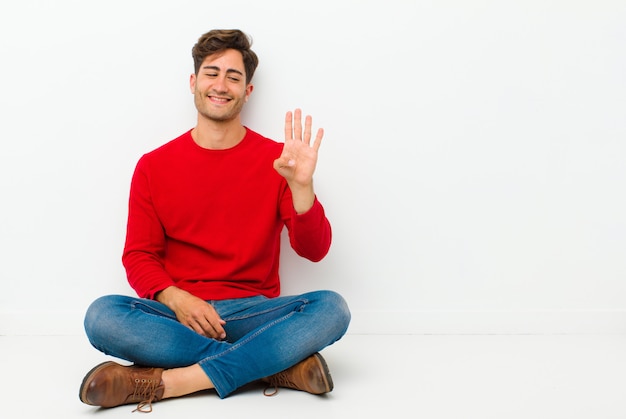 smiling and looking friendly, showing number four or fourth with hand forward, counting down