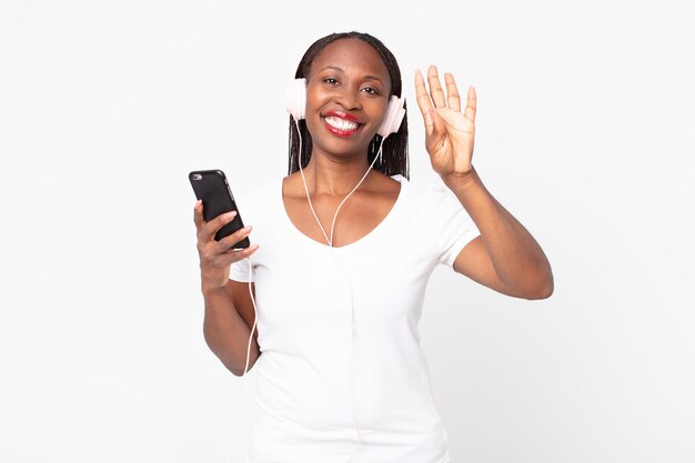 Smiling and looking friendly, showing number four with headphones and a smart phone