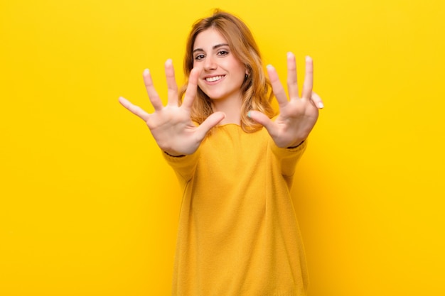 smiling and looking friendly, showing number nine or ninth with hand forward, counting down