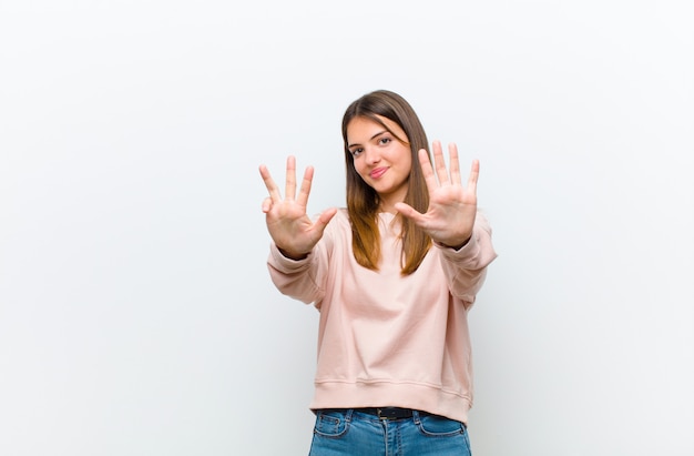 smiling and looking friendly, showing number nine or ninth with hand forward, counting down