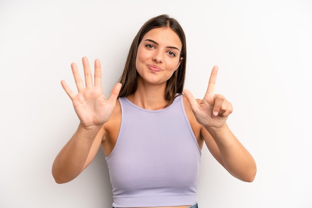 Smiling and looking friendly showing number seven or seventh with hand forward counting down