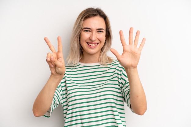 Smiling and looking friendly showing number seven or seventh with hand forward counting down