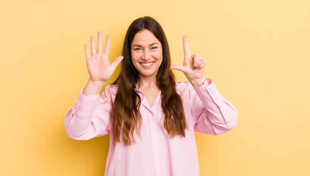 Smiling and looking friendly showing number seven or seventh with hand forward counting down