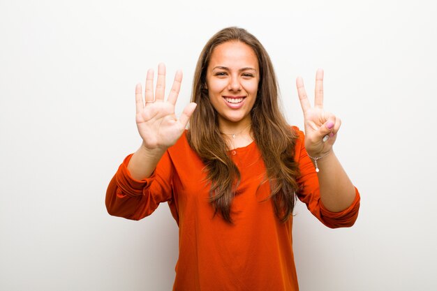 smiling and looking friendly, showing number seven or seventh with hand forward, counting down