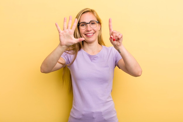 Smiling and looking friendly showing number six or sixth with hand forward counting down