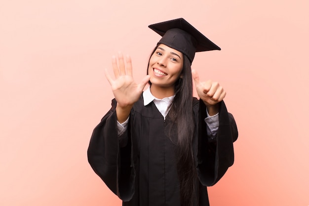 smiling and looking friendly, showing number six or sixth with hand forward, counting down