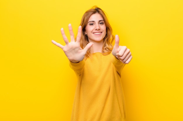 smiling and looking friendly, showing number six or sixth with hand forward, counting down