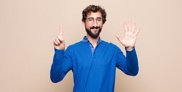 smiling and looking friendly, showing number six or sixth with hand forward, counting down