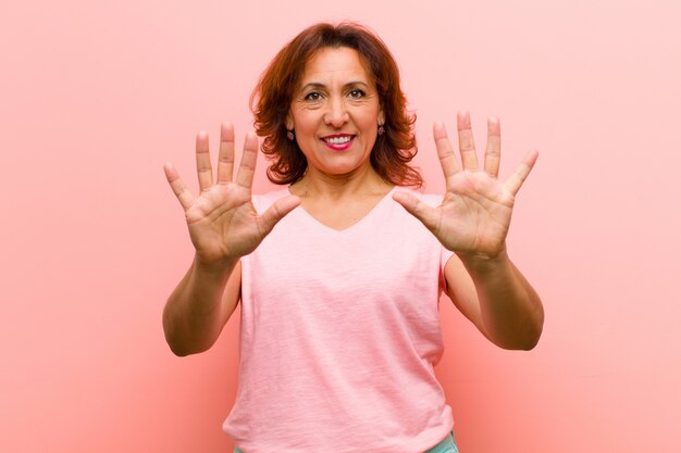 Photo smiling and looking friendly, showing number ten or tenth with hand forward, counting down