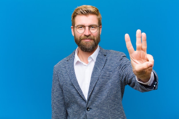 Smiling and looking friendly, showing number three or third with hand forward, counting down