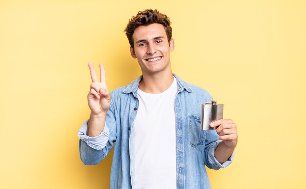 Smiling and looking friendly, showing number two or second with hand forward, counting down. alcohol flask concept