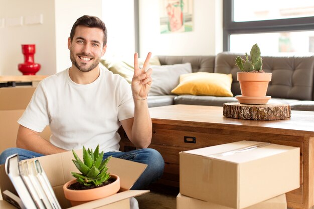 smiling and looking friendly, showing number two or second with hand forward, counting down