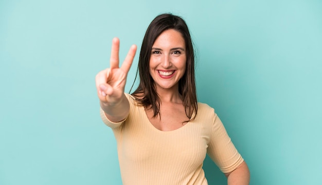 Smiling and looking friendly showing number two or second with hand forward counting down