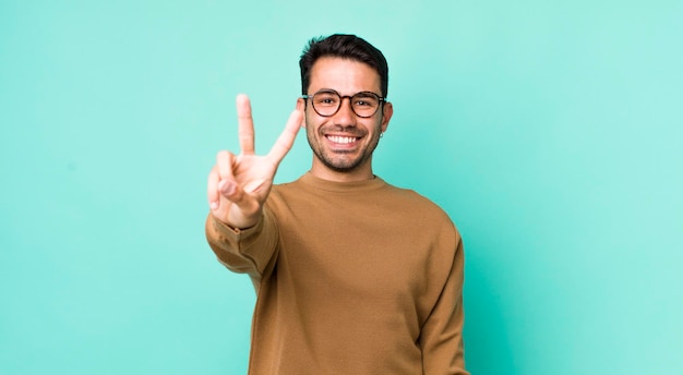 Smiling and looking friendly showing number two or second with hand forward counting down