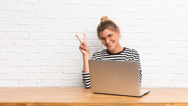 smiling and looking friendly, showing number two or second with hand forward, counting down