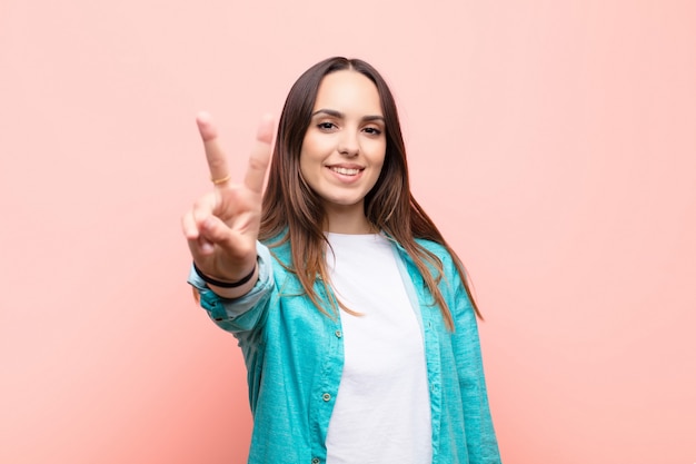 smiling and looking friendly, showing number two or second with hand forward, counting down