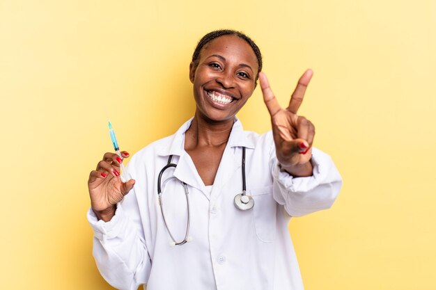 Sorridere e guardare felice vittoria spensierata e positiva o pace con una mano medico e concetto di siringa