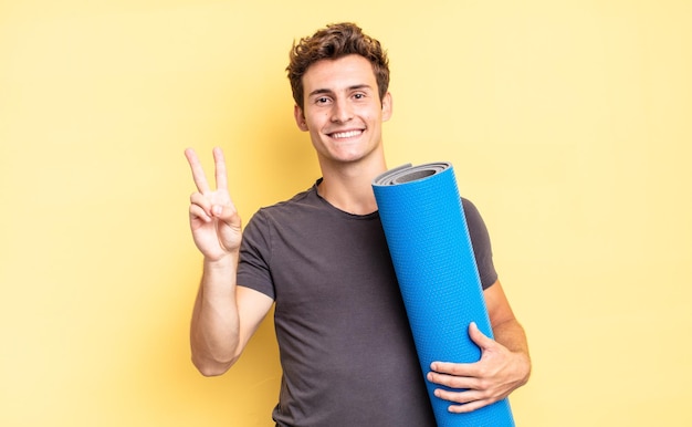 Smiling and looking happy, carefree and positive, gesturing victory or peace with one hand. yoga mat concept