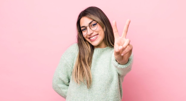 Smiling and looking happy carefree and positive gesturing\
victory or peace with one hand