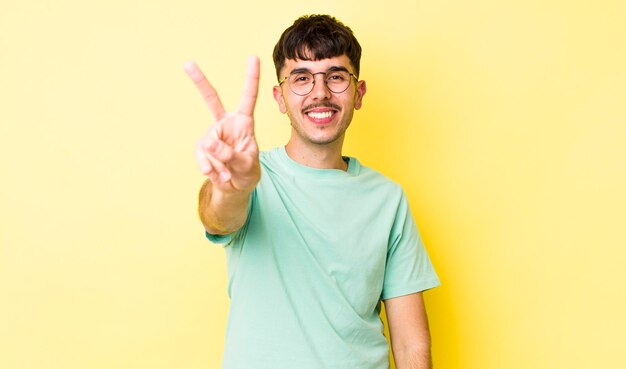 Photo smiling and looking happy carefree and positive gesturing victory or peace with one hand