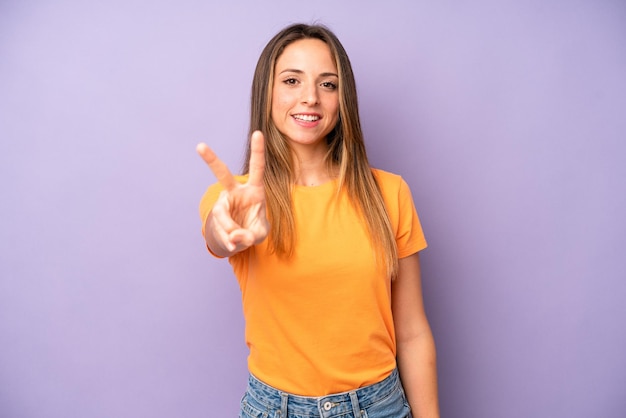 Smiling and looking happy carefree and positive gesturing
victory or peace with one hand