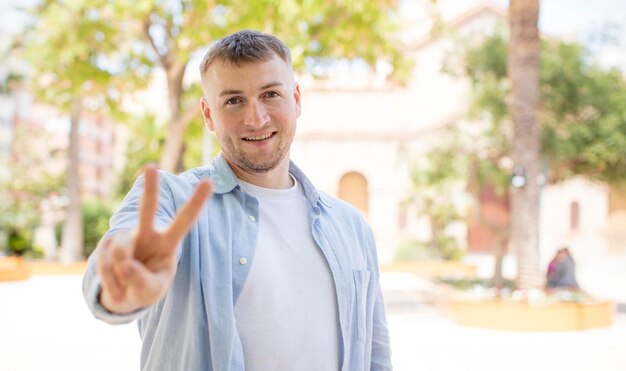 Smiling and looking happy carefree and positive gesturing victory or peace with one hand