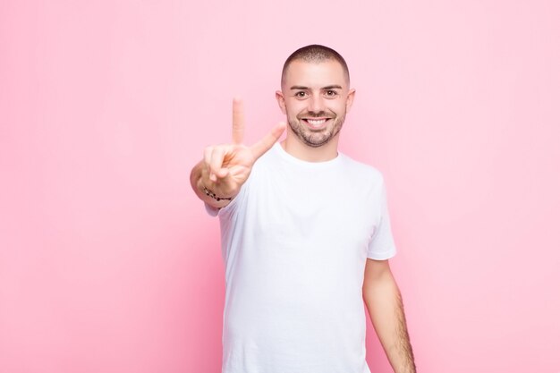 smiling and looking happy, carefree and positive, gesturing victory or peace with one hand