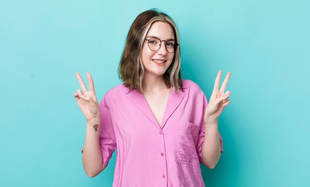 Smiling and looking happy friendly and satisfied gesturing victory or peace with both hands