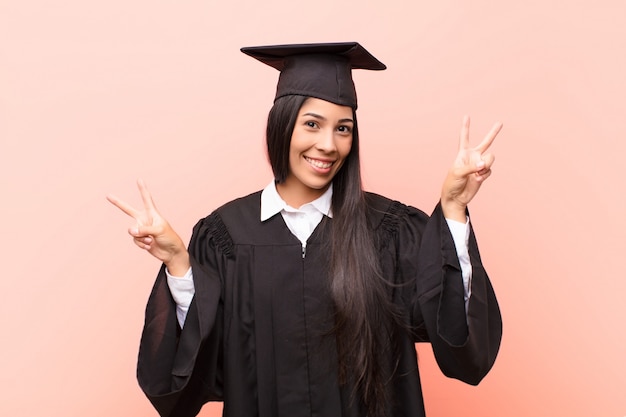 smiling and looking happy, friendly and satisfied, gesturing victory or peace with both hands