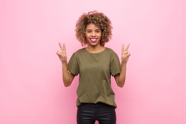 smiling and looking happy, friendly and satisfied, gesturing victory or peace with both hands