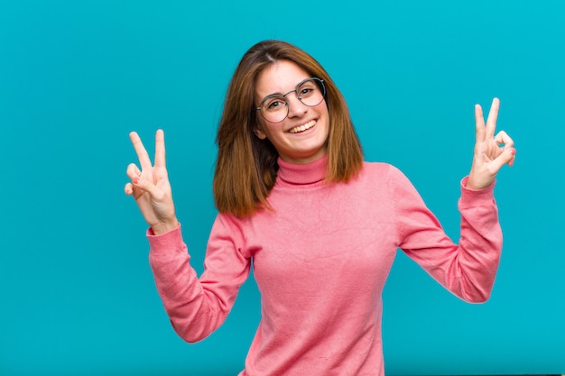 Smiling and looking happy, friendly and satisfied, gesturing victory or peace with both hands