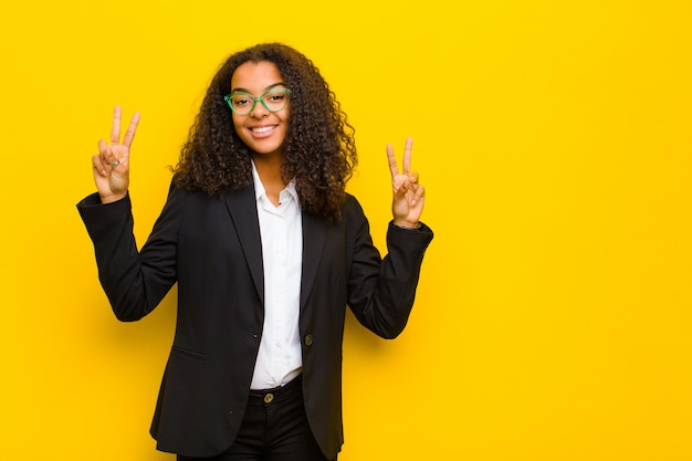 smiling and looking happy, friendly and satisfied, gesturing victory or peace with both hands