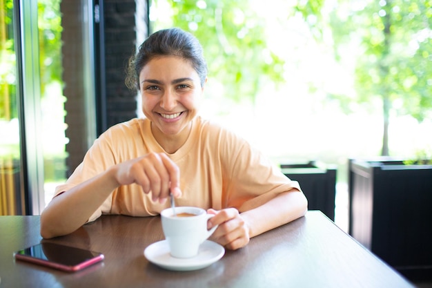 外でコーヒーを飲みながら笑顔の素敵な若い女性