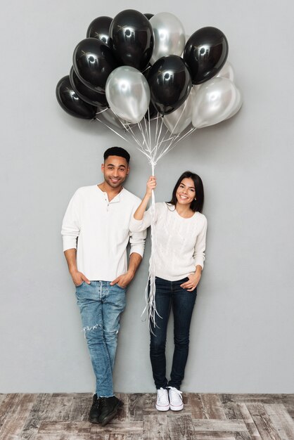 Smiling loving couple holding balloons.