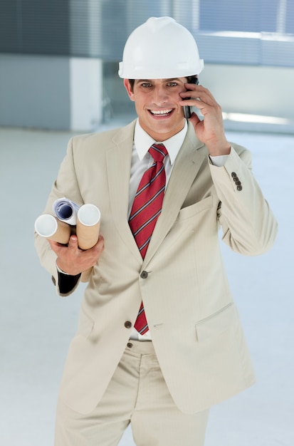 Foto architetto maschio sorridente con l'elmetto protettivo sul telefono