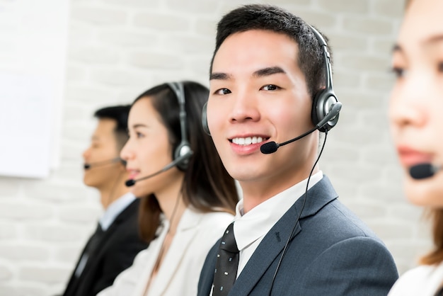 コールセンターで男性のアジアの顧客サービステレマーケティングエージェントを笑顔