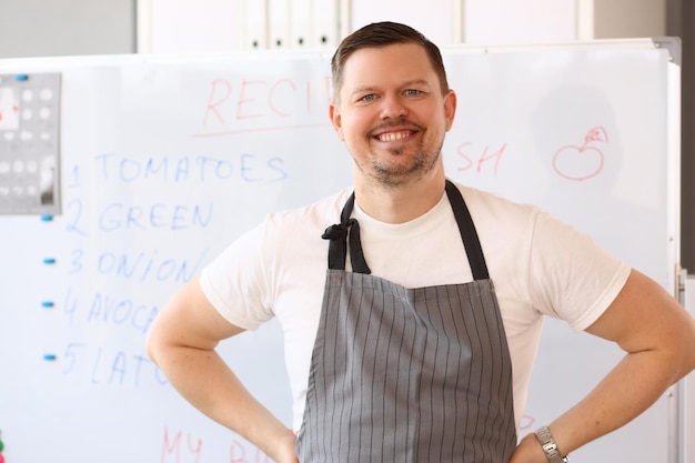 Smiling male chef in apron conducts online cooking training and recipes for delicious dishes