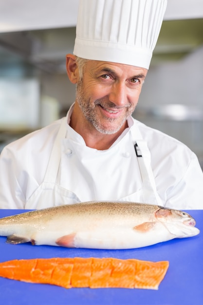 Vassoio maschio sorridente della tenuta del cuoco unico di pesce crudo in cucina